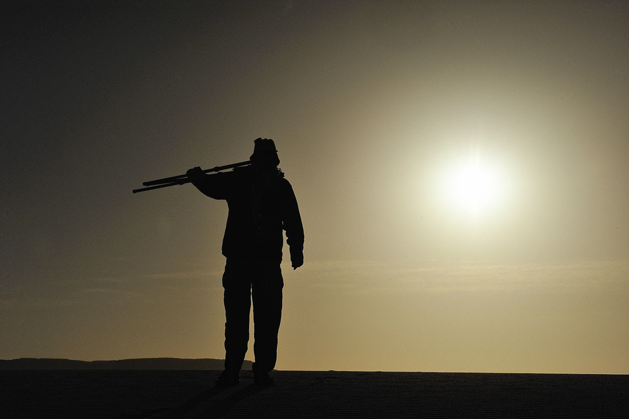 Amar Guillen, photographer walking in the desert under the sun at sunset.