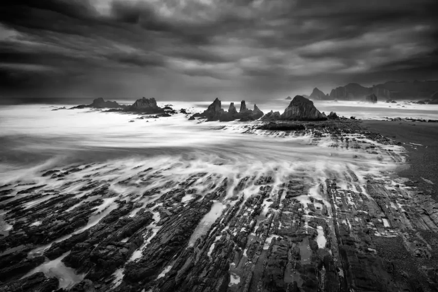Seascape of Asturias in Spain in black and white.The waves of the Atlantic Oceans break on the rocks of the shore or on the cliffs.