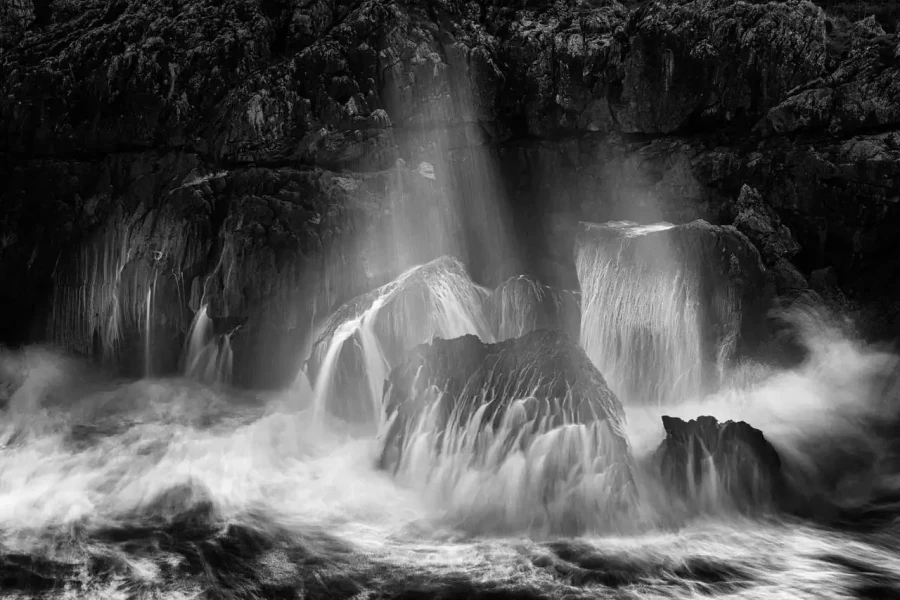 Seascape of Asturias in Spain in black and white.The waves of the Atlantic Oceans break on the rocks of the shore or on the cliffs.