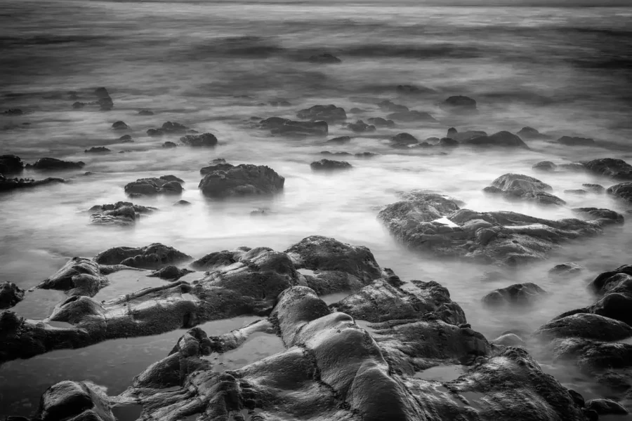 Seascape of Asturias in Spain in black and white.The waves of the Atlantic Oceans break on the rocks of the shore or on the cliffs.