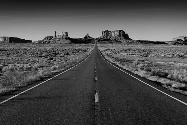 Photo en noir et blanc d'une route allant vers Monument Valley en Arizona. Photographie par Amar Guillen, artiste photographe.
