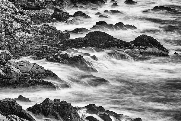 Vagues s'écrasant sur des rochers sur la côte du finistère sud en Bretagne en France. Photographie d'art en noir et blanc par Amar Guillen, artiste photographe.