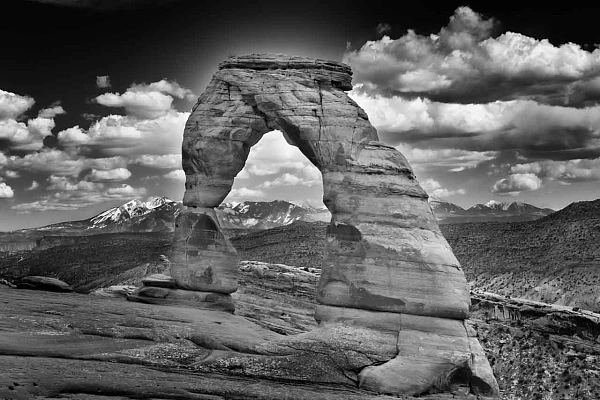 Une photo d'art en noir et blanc de Delicate Arch dans le parc national des Arches dans l'Utah aux Etats-Unis. Photographie par Amar Guillen, artiste photographe. 