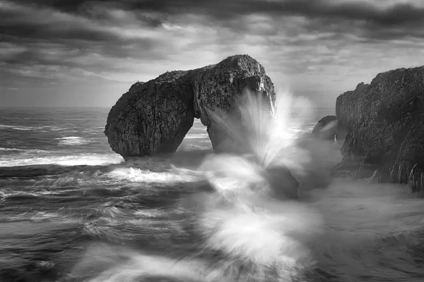 Vagues de l'océan Atlantique se brisant sur les rochers dans les Asturies en Espagne: El Castro de las Caviotas. Photographie d'art en noir et blanc par Amar Guillen, artiste photographe.