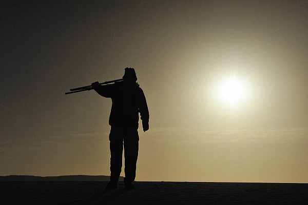 Amar Guillen, photographe, marchant dans le désert au crépuscule.